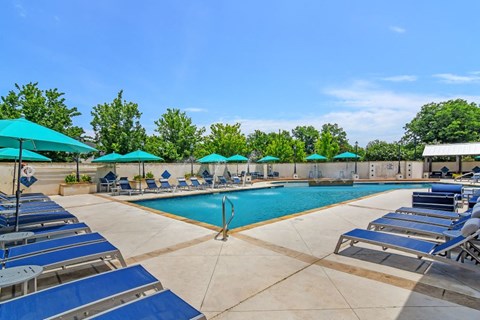 a pool with lounge chairs and umbrellas at the preserve at great pond apartments in winds